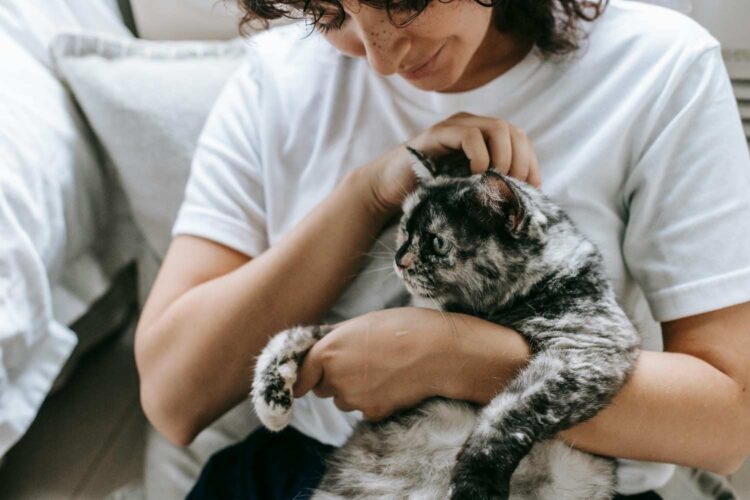 A woman holding her cat on her arms