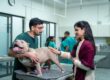A vet examines a dog with its owner at a veterinary clinic